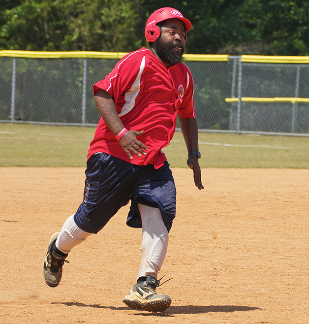 A man wearing a red baseball jersey and red helmet runs on a baseball field